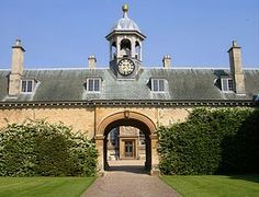 a large building with a clock on it's face in front of some bushes