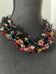 Accessories are a great way to revamp an outfit--and a statement necklace is the way to go. This beaded statement black Bib necklaces is great for dressing up your party dresses with wow-effect. The necklace is beaded using Czech glass seed beads and glass flowers. Black background and multicolored shiny colors of flowers makes this necklace rich, bright with luxurious look. The necklace measures approximately 48 cm. It is called a statement necklace for a reason--it is unique, chunky, and grabs Unique Black Beaded Chain Necklace, Unique Black Necklace With Beaded Chain, Black Bib Necklace With Colorful Beads For Gift, Gift Black Bib Necklace With Colorful Beads, Black Round Bead Bib Necklaces For Party, Black Beaded Costume Jewelry Necklaces For Party, Unique Black Beaded Necklace For Party, Unique Black Beads Necklace For Party, Black Beaded Costume Jewelry Necklace For Party