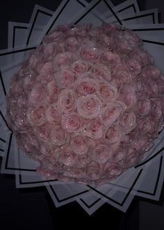 a bouquet of pink roses on top of a white paper plate in front of a black background