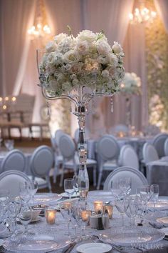 a tall centerpiece with white flowers and candles sits on top of a round table