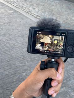 a person holding up a camera to take a photo with an umbrella on the street