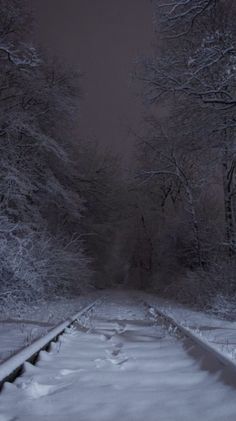 the train tracks are covered in snow at night