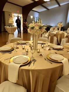 the table is set with gold and white plates, silverware, and centerpieces