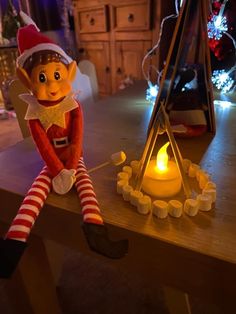 an elf sitting on a table next to a lit candle