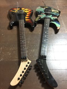 two electric guitars sitting on top of a wooden floor