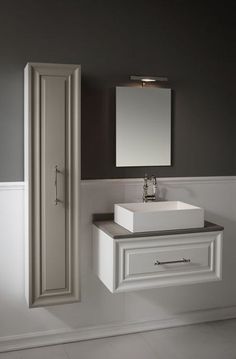 a white sink sitting under a bathroom mirror next to a wall mounted cabinet and door