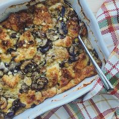 a casserole dish with mushrooms in it and a spoon on the side next to some napkins