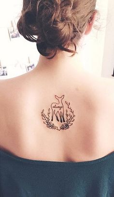 a woman with a deer tattoo on her upper back shoulder and behind her is a mirror