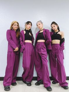 three women standing next to each other in purple outfits