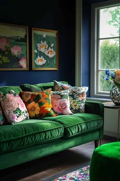 a green couch sitting in front of a window next to a table with flowers on it