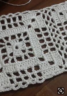 a white crocheted table runner sitting on top of a wooden floor next to a pair of scissors