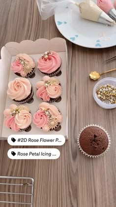 cupcakes with pink frosting in a box on a table next to other desserts