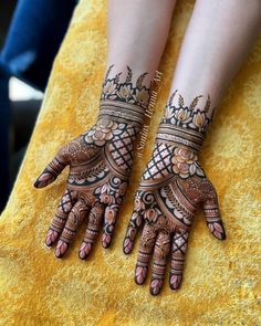 two hands with henna tattoos on them