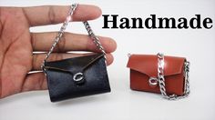 two small purses that are being held in one hand and the other has a chain attached