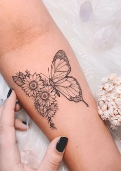 a woman's arm with a butterfly and flowers tattoo on the left side of her arm