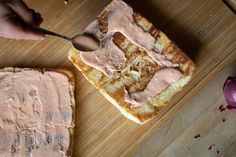 someone is spreading peanut butter on top of some toasted bread with pink frosting