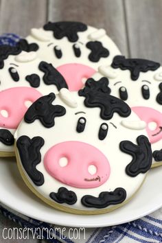 decorated cookies with black and white cow faces on top of each other, sitting on a plate