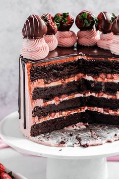 a chocolate cake with strawberries on top is cut in half to show the layers