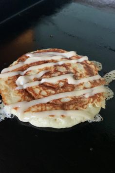 a waffle covered in icing sitting on top of a black counter next to a frying pan