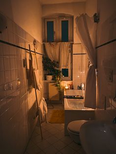 a dimly lit bathroom with two toilets and a bathtub in the corner, next to a window