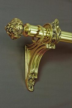 an ornate gold curtain rod with lion head handles and finial, on a gray background