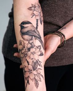 a woman's arm with a bird and flowers on it