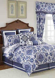 a bed with blue and white comforter in a bedroom next to a dresser, mirror and chair