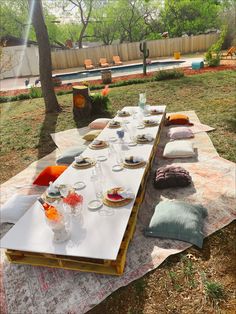 a long table with plates and glasses on it in the middle of an outdoor area