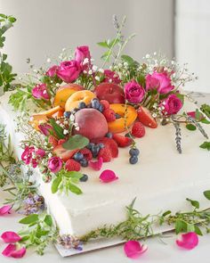 a white cake topped with fruit and flowers