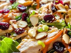 a salad with chicken, cranberries, almonds and lettuce