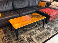 a living room with black leather couches and wooden tables