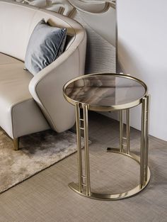 a white couch sitting next to a glass table on top of a carpeted floor