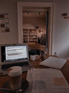 an open laptop computer sitting on top of a wooden table next to a cup of coffee