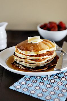 a stack of pancakes on a plate with butter and syrup