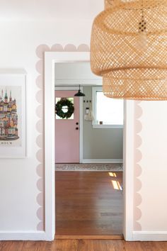 an open door leading to a living room with pink walls and white trim on the wall