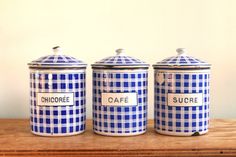 three blue and white canisters sitting on top of a wooden table