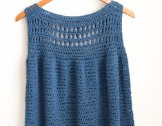 a blue crocheted top hanging on a wooden hanger