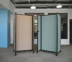 three partitions in an empty room with light blue walls and carpeting on the floor