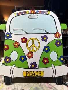 a green and white vw bus with flowers painted on the side is sitting in front of a wall