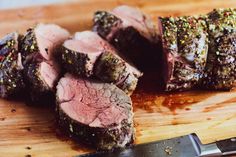 sliced up meat sitting on top of a cutting board next to a knife