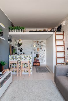 a living room filled with furniture next to a white brick wall and a ladder leading up to the top floor