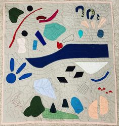 a quilted wall hanging on the side of a building with different colored shapes and sizes