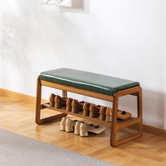 a wooden bench with shoes on it in front of a white wall and hardwood floor