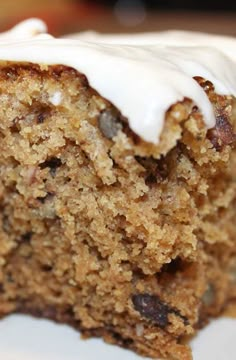 a close up of a piece of cake on a plate with icing and nuts