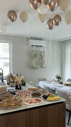 a table filled with food and balloons hanging from the ceiling