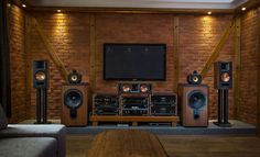 a living room with speakers and a television on the wall in front of a brick wall