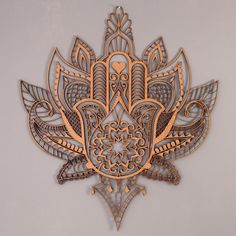 an intricately designed metal wall hanging on the side of a white wall with gold accents