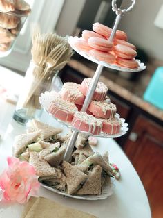 three tiered trays with sandwiches and pastries on them sitting on a table