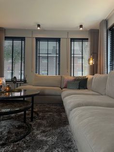 a living room filled with furniture and windows covered in blind shades on top of them