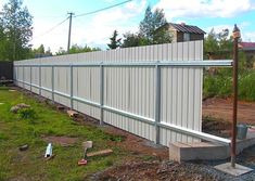 an image of a fence that is being built in front of a house with grass and dirt